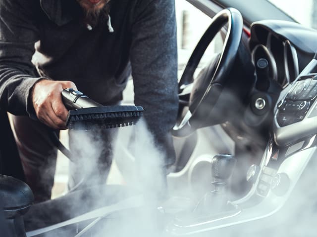 Hombre limpiando interior de auto con vapor