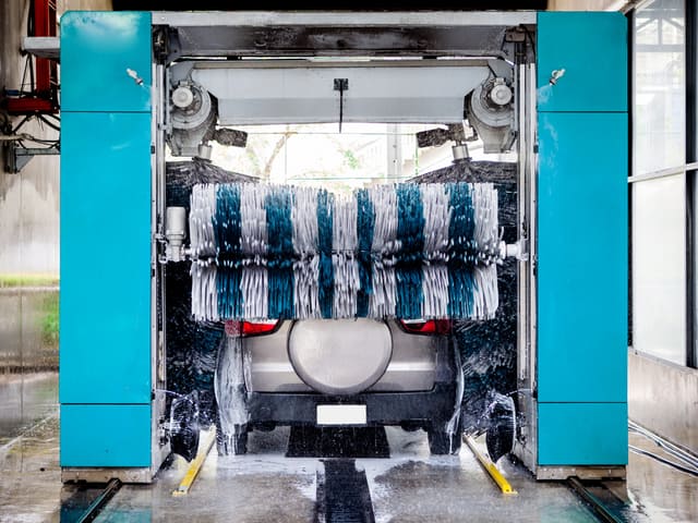 Auto gris en túnel de lavado automático