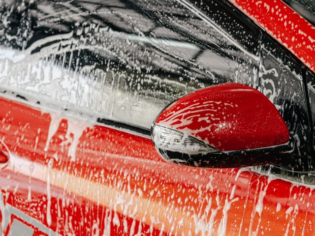 Espejo lateral rojo de auto siendo lavado