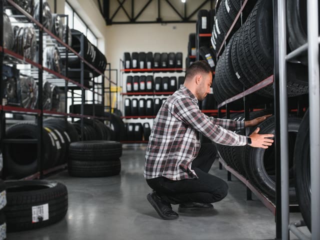 Hombre seleccionando llantas en almacén automotriz