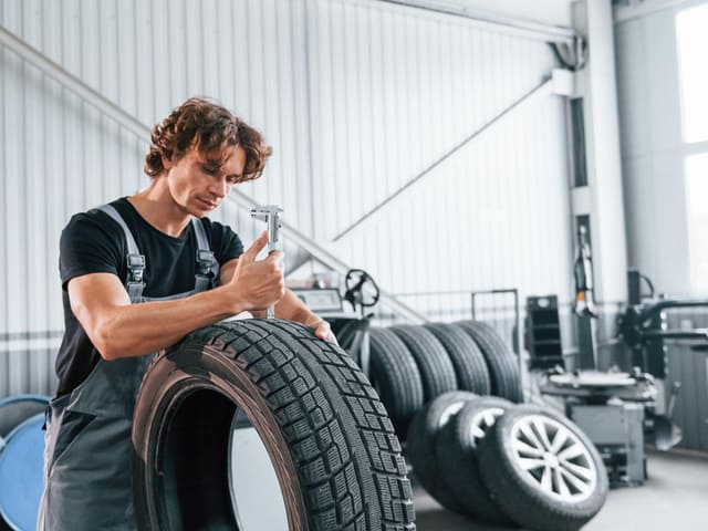 Mecánico revisando llanta en taller automotriz