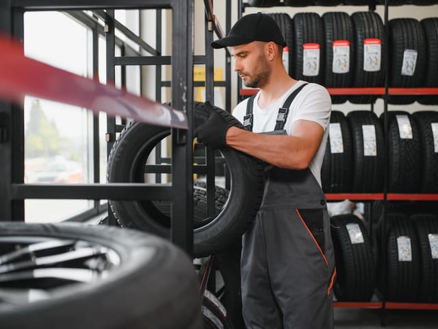 Mecánico organizando llantas en taller automotriz