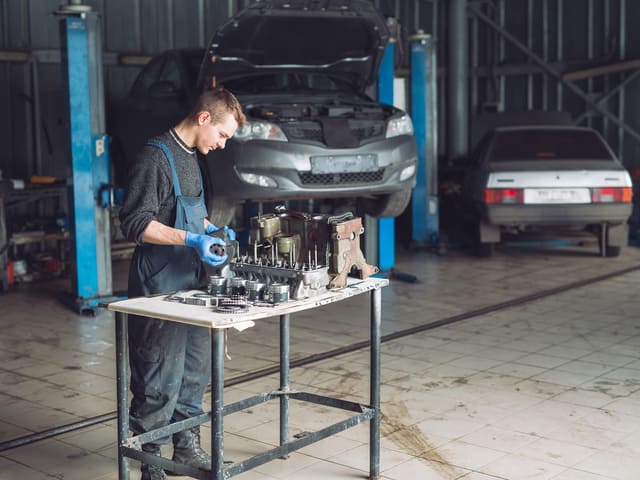 Mecánico trabajando en taller con partes de automóvil