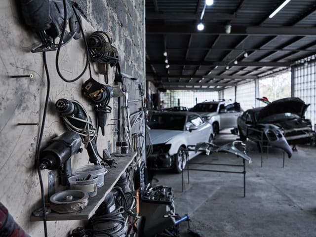 Taller mecánico con autos y herramientas colgadas