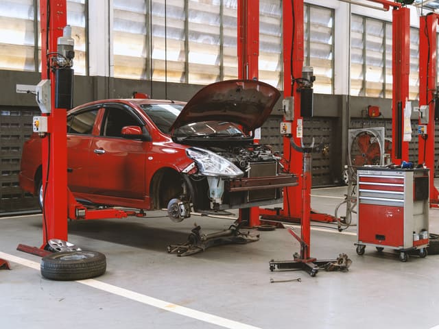 Auto rojo en reparación en taller mecánico