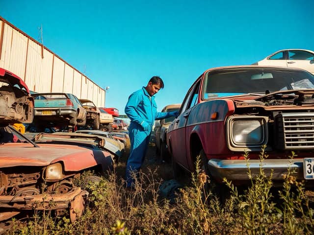 Hombre revisando automóviles viejos en deshuesadero
